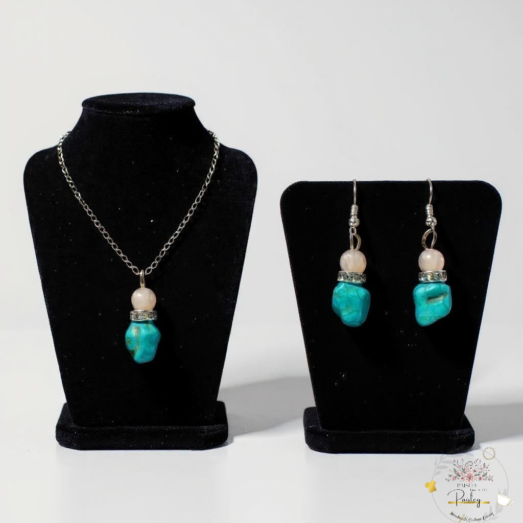 Jewelry set with necklace and earrings handmade turquoise and rose quartz on black stands against a white background