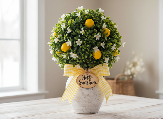 Decorative topiary with lemons and flowers in a pot on a table.