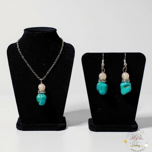 Jewelry set with necklace and earrings handmade turquoise and rose quartz on black stands against a white background