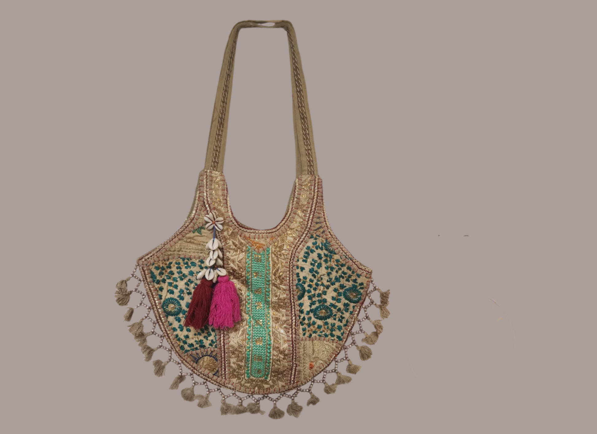 Handcrafted bohemian tote bag featuring orange base with intricate embroidery, purple and white floral patterns, shell embellishments, yellow tassels, and traditional Indian mirror work detailing