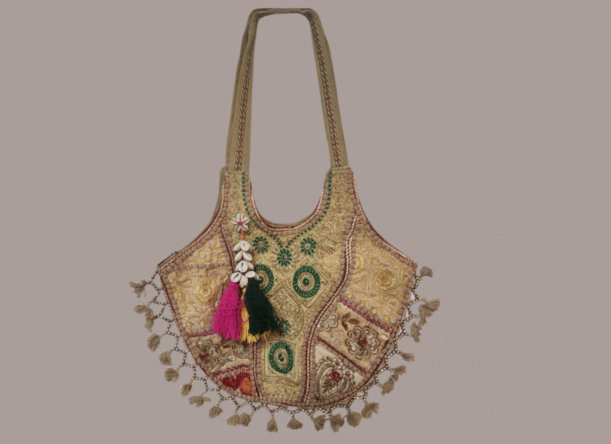 Handcrafted bohemian tote bag featuring orange base with intricate embroidery, purple and white floral patterns, shell embellishments, yellow tassels, and traditional Indian mirror work detailing
