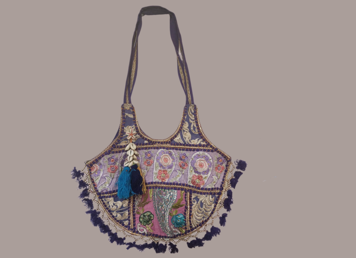 Handcrafted bohemian tote bag featuring orange base with intricate embroidery, purple and white floral patterns, shell embellishments, yellow tassels, and traditional Indian mirror work detailing