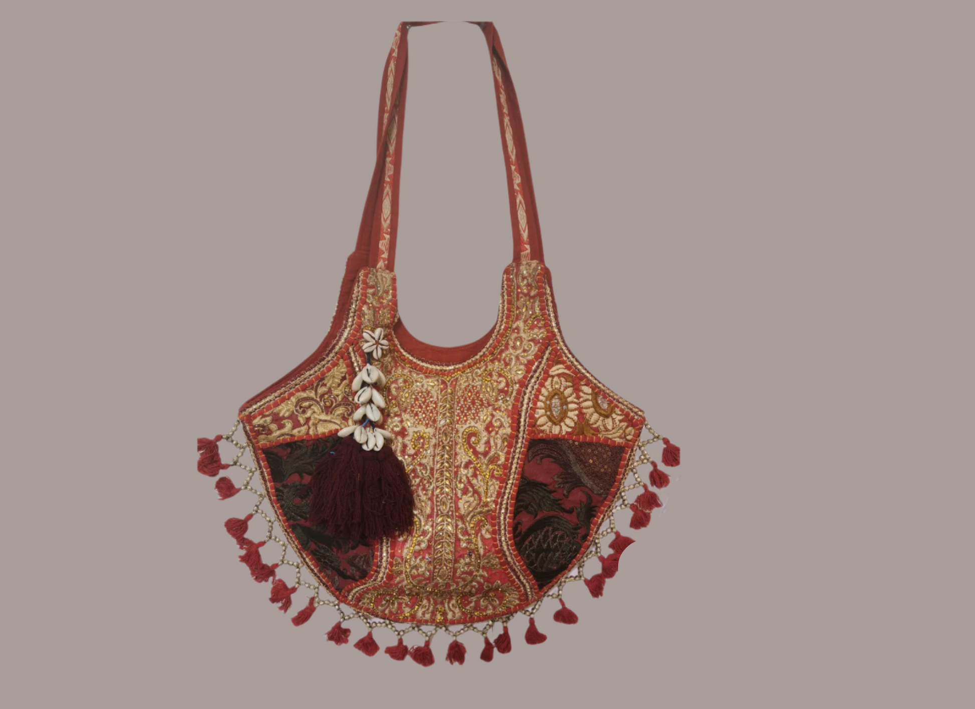 Handcrafted bohemian tote bag featuring orange base with intricate embroidery, purple and white floral patterns, shell embellishments, yellow tassels, and traditional Indian mirror work detailing